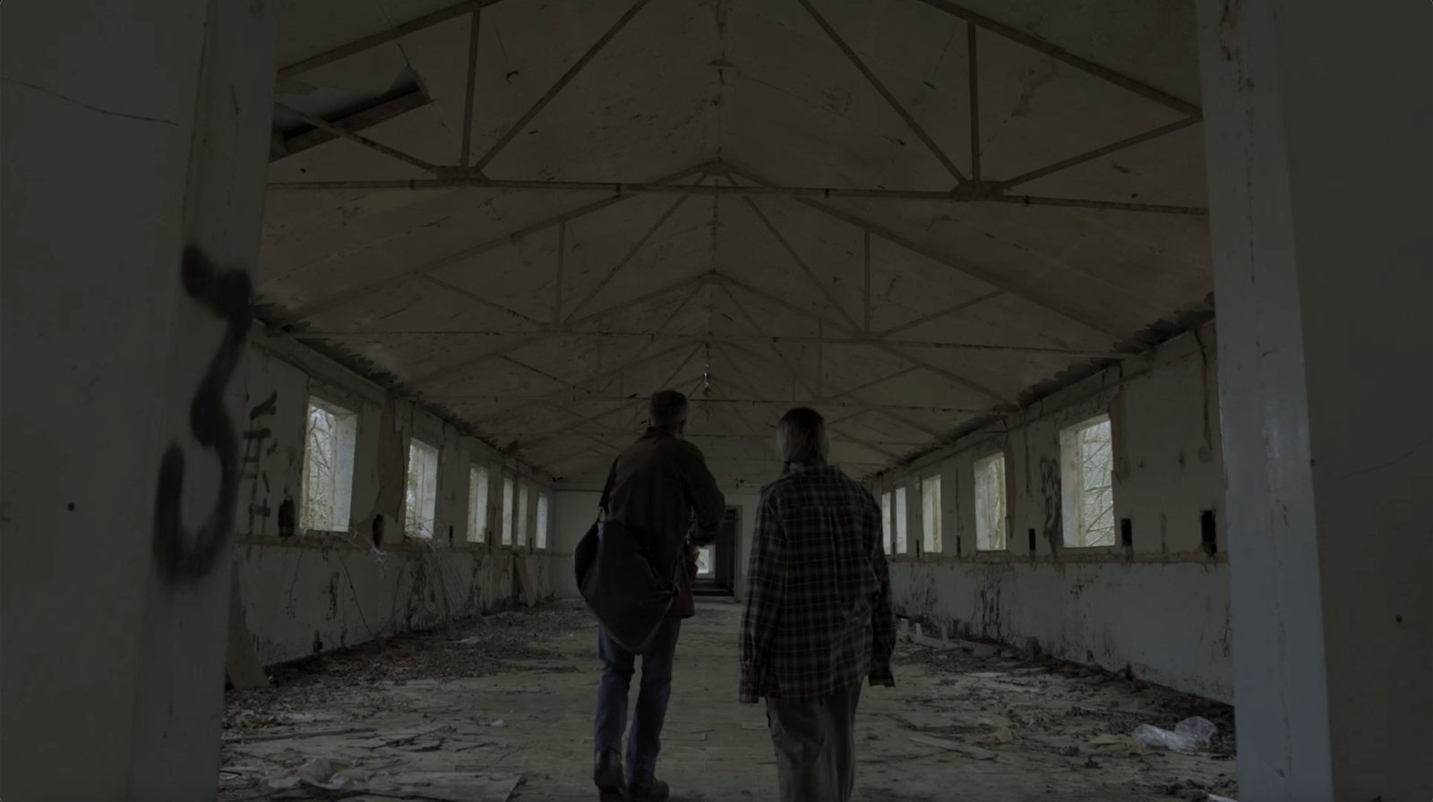 Two characters walking through a derelict hall in Roots