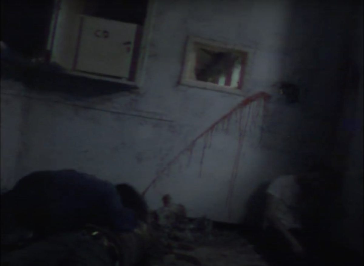 Grainy Mini DV camcorder footage of a blood-streaked wall in Roots